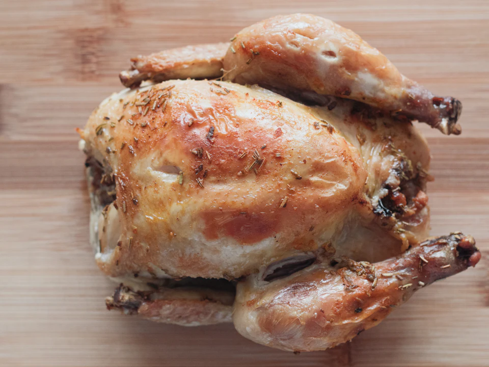 Frango assado inteiro, dourado, numa tábua.
