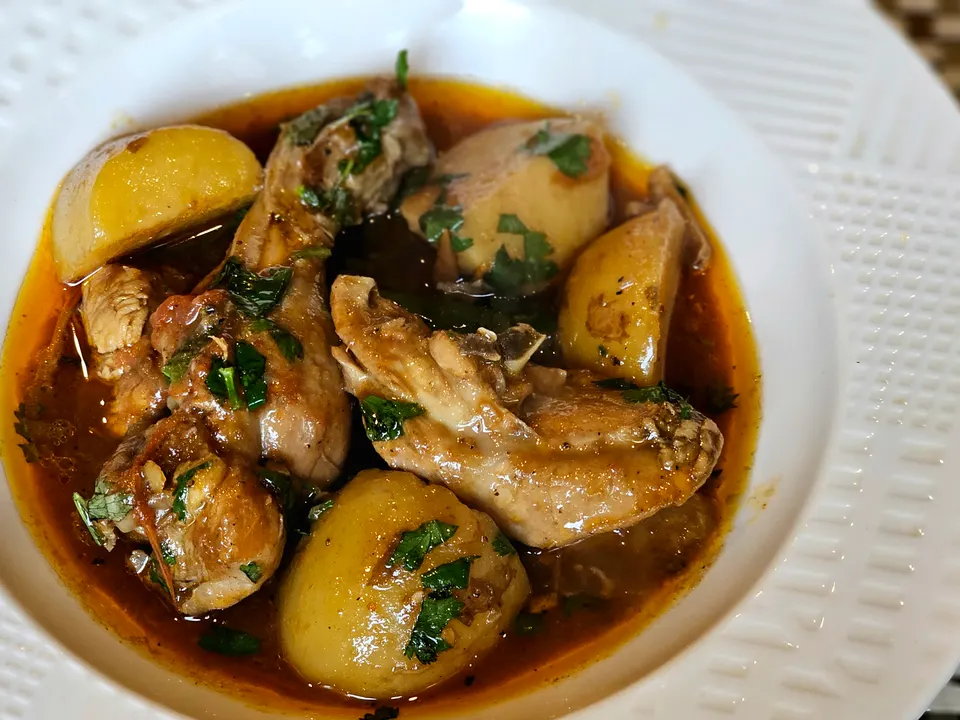 Frango ensopado com batatas, num prato fundo.